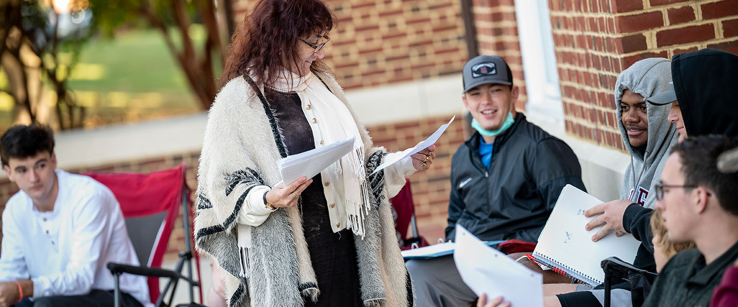 a professor handing out papers in an outdoor classroom