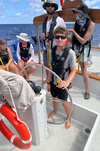 Watson Grabar at the helm of a sailboat
