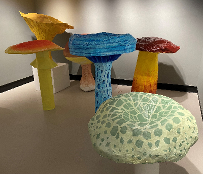 brightly colored paper mach mushrooms on display in an art gallery