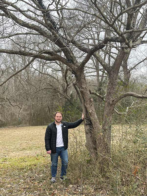 Jacob Johnson stands by a tree