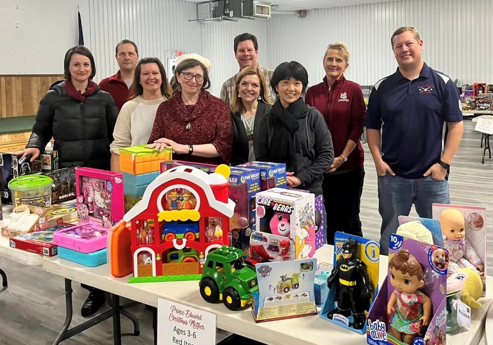 a group of faculty and staff behind a table of donated toys