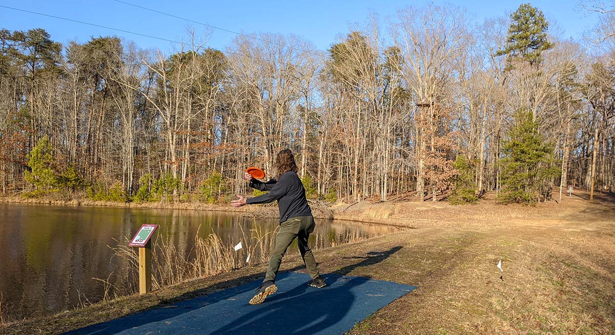 a student tossing a disc into the basket