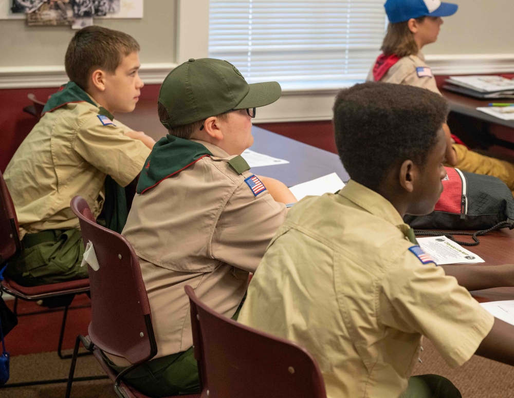 boy scouts in uniform sitting at a desk listening