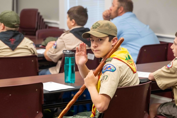 a boy scout in uniform waving to the camera