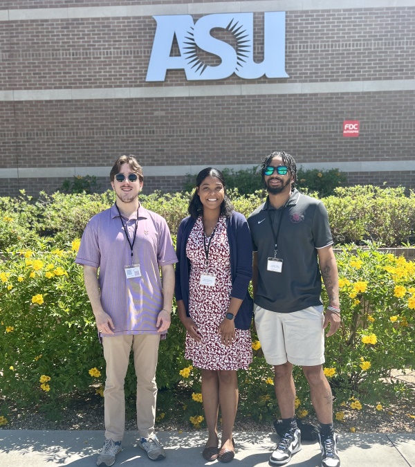 students and professor standing beside a "ASU" conference sign