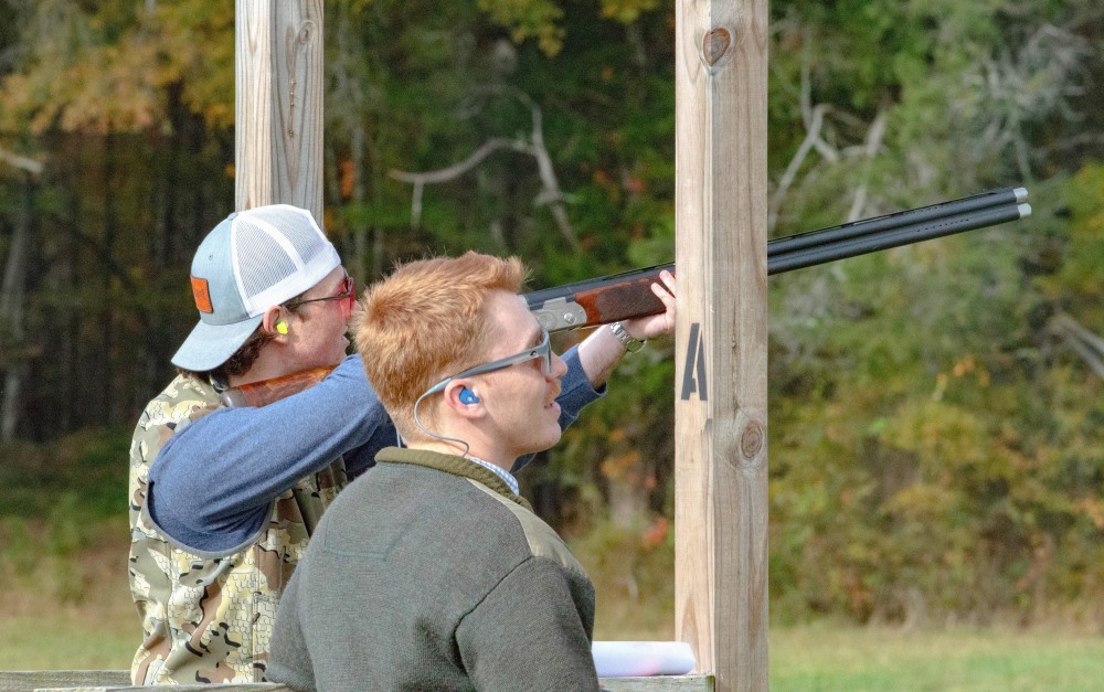 student aiming a gun at a sporting clays range