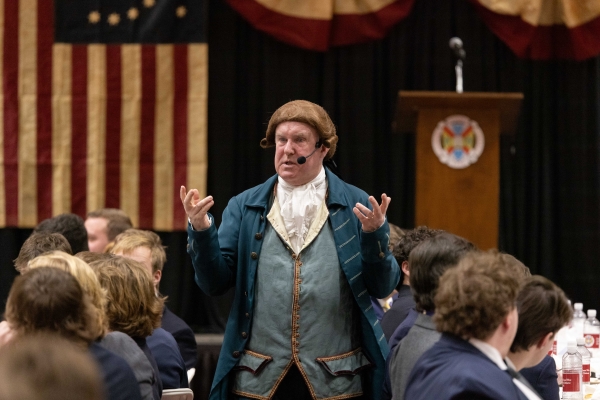 a reenactor dressed as an 18th century man delivering a speech