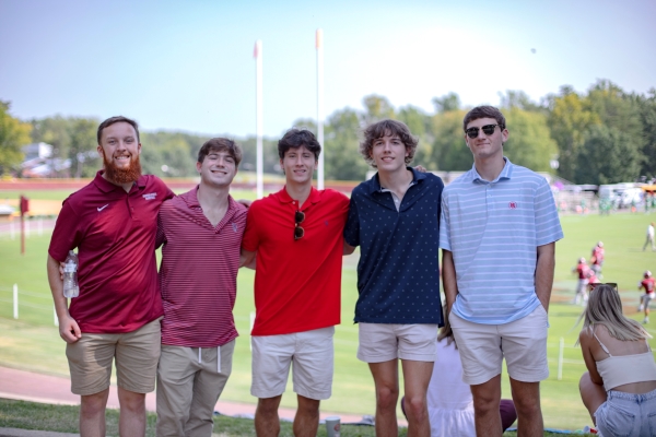 Adam Brazil with his friends standing in front of the footballe field