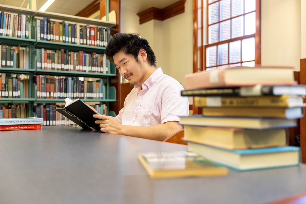 Ben Jia reading a book in the library