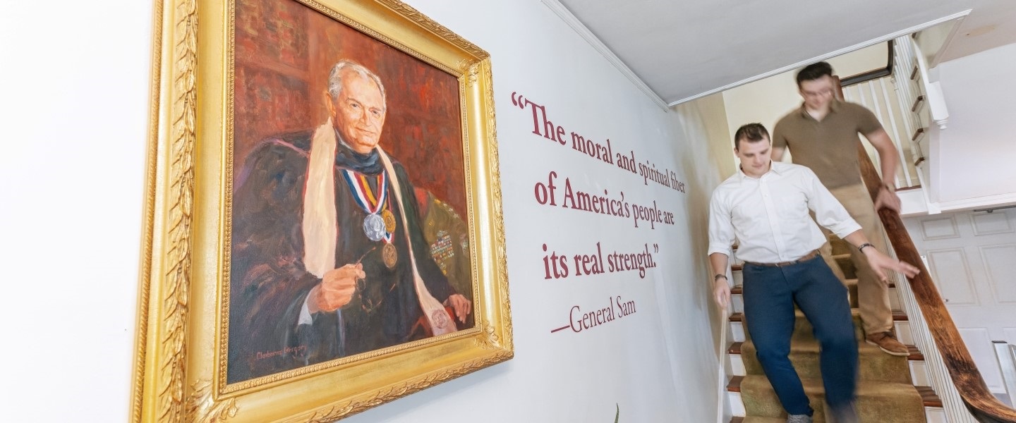 Hampden-Sydney College students walking down stairs in front of Sam Wilson's portrait